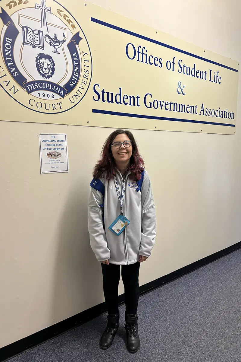 A girl smiling with a sign behind her that says "Offices of Student Live & Student Government Association"