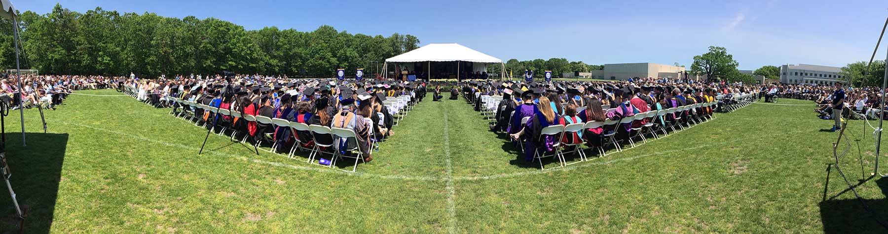 Students & Faculty sitting in white chairs at commencement