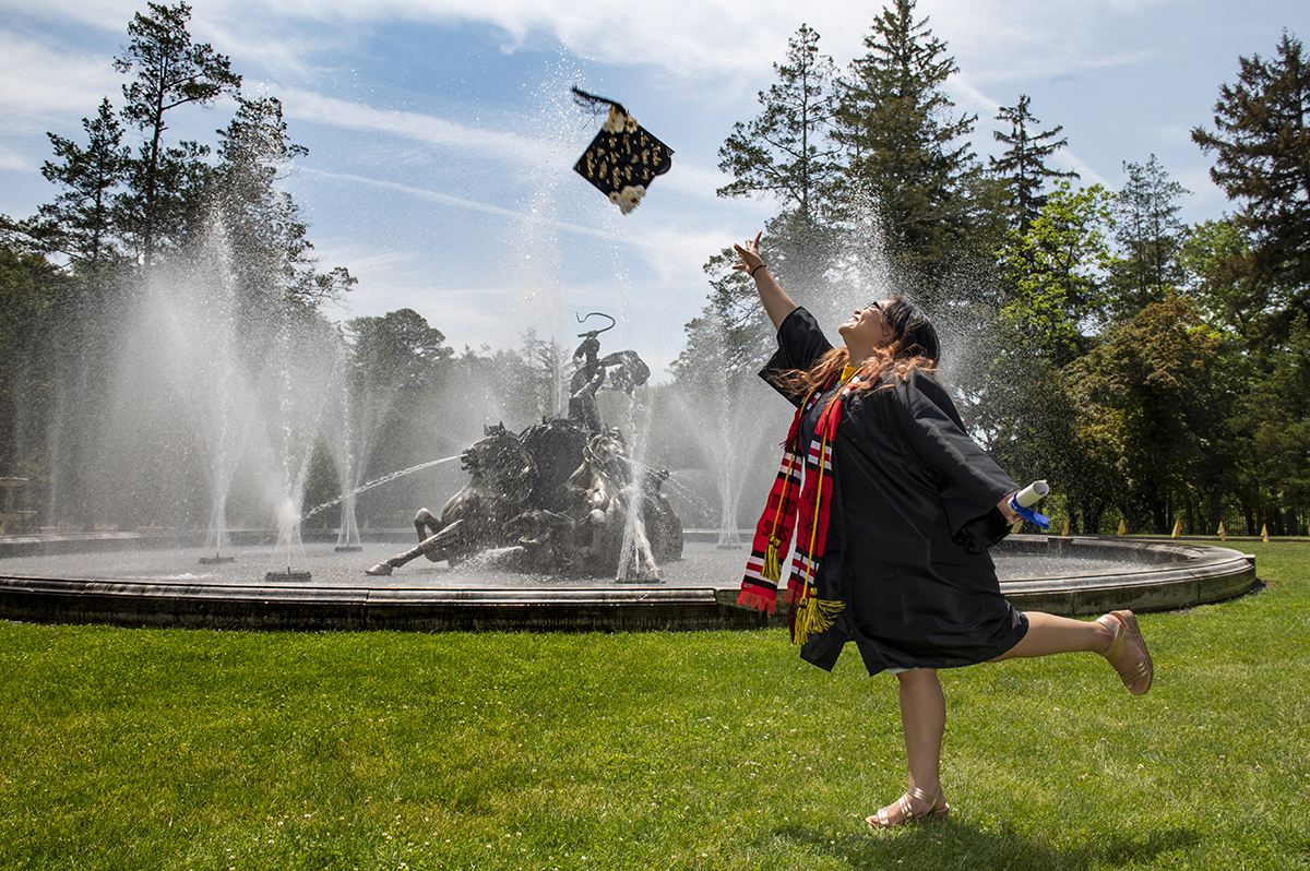 Ashley Rosales '21 tosses her cap in front of the Apollo Fountain