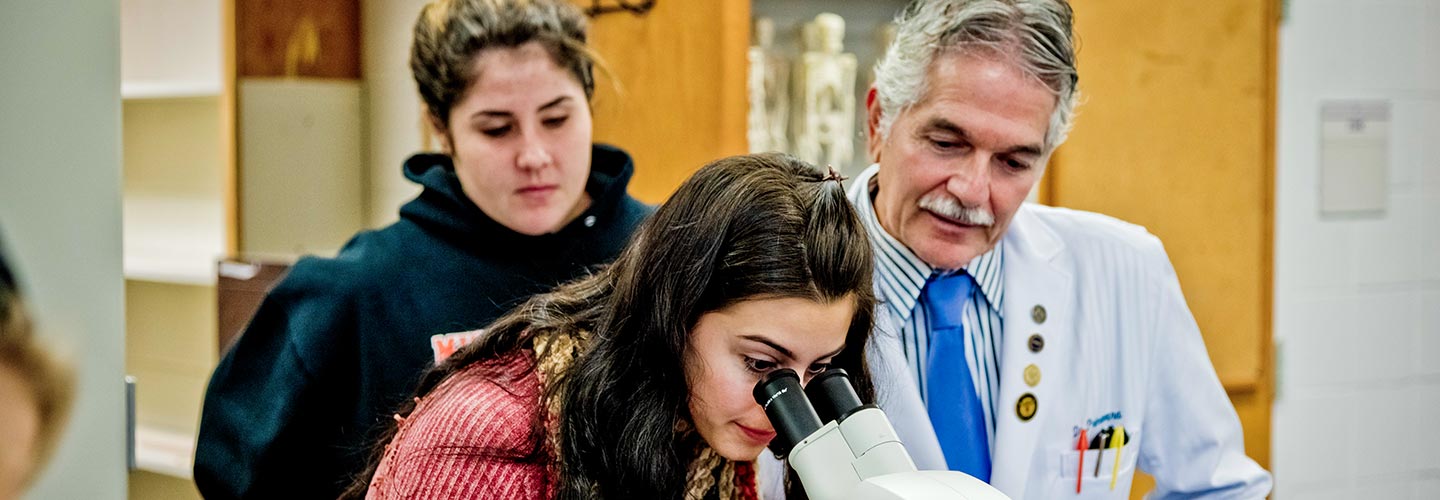 Student with her teacher looking through a microscope