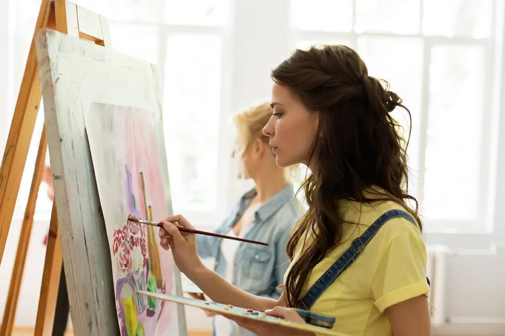 A Bachelor of Arts in Visual Art female student painting at an easel