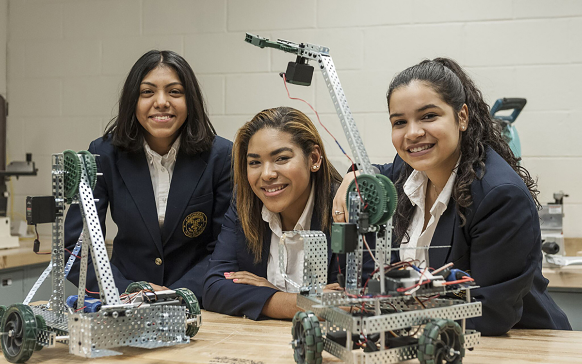 Three students creating small robot machines