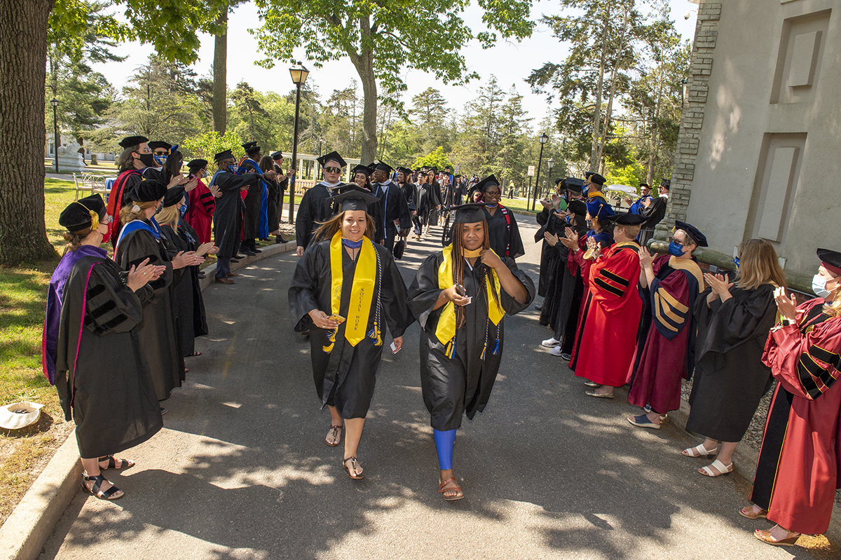 graduates process past faculty at Commencement
