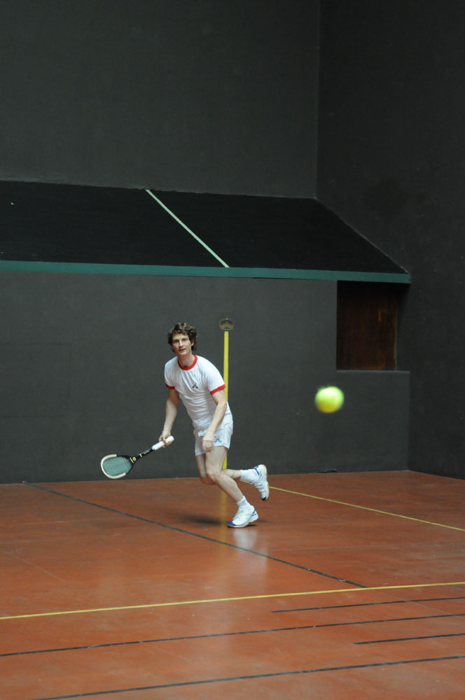 Man running for tennis ball with tennis racket.