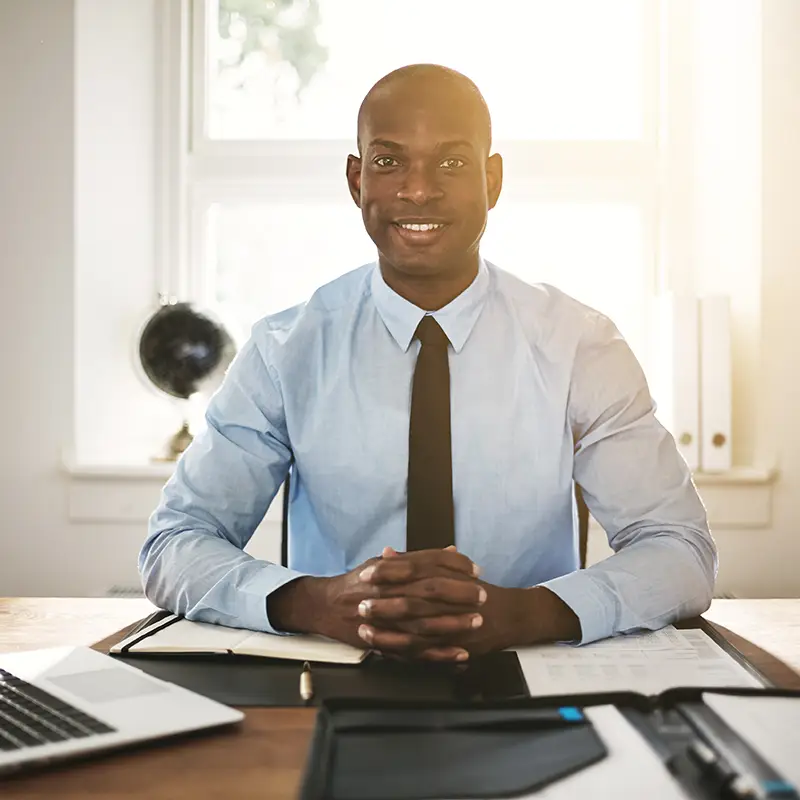 A man sitting at a desk wearing a shirt and tie