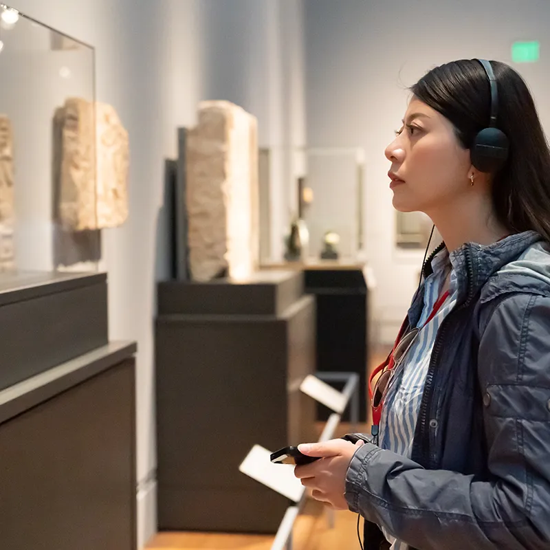 A woman in a History museum taking an audio guided tour