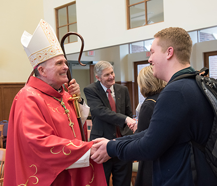 Priest shaking a student's hand