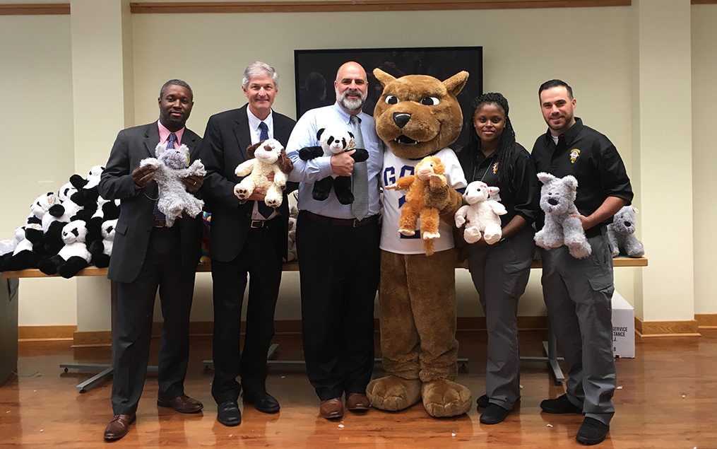GCU faculty holding stuff animals and standing next to the GCU lion mascot