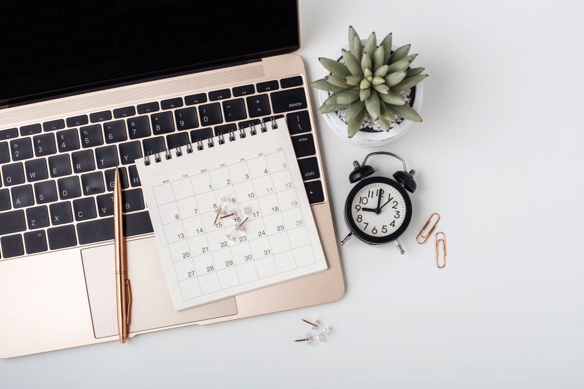 laptop with a calendar, pen and clock in the photo