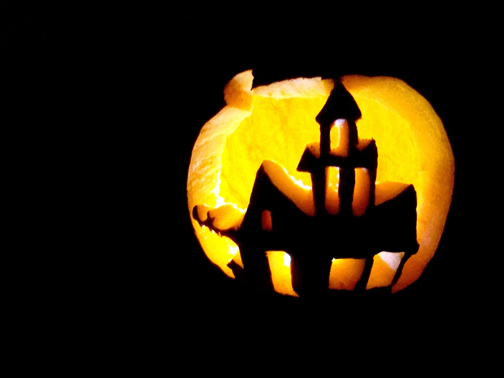 A haunted house cutout in a jack-o-lantern pumpkin for Halloween.