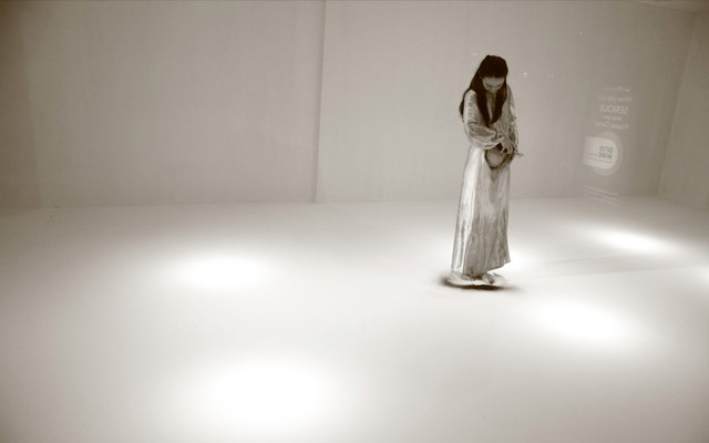 White picture of a woman wearing white dress looking to the floor