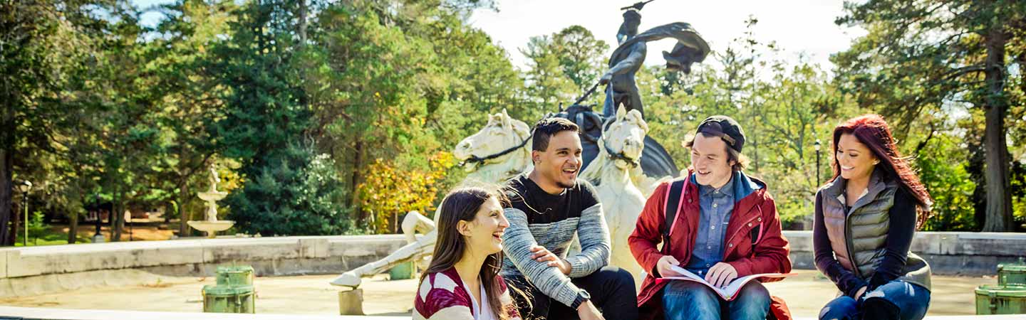 Four students smiling and talking in front of GCU fountain