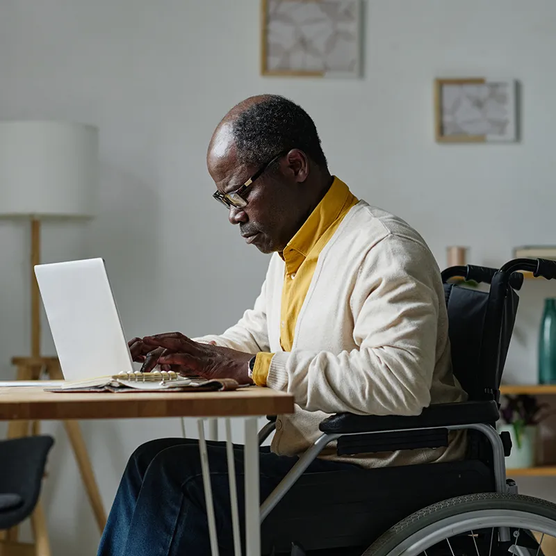 African American male online learning student with a disability typing on laptop
