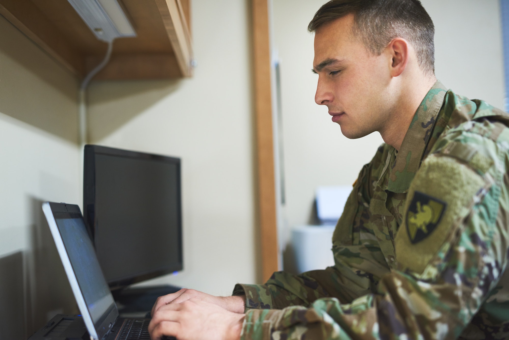 Shot of a young soldier using a laptop in the dorms of a military academy