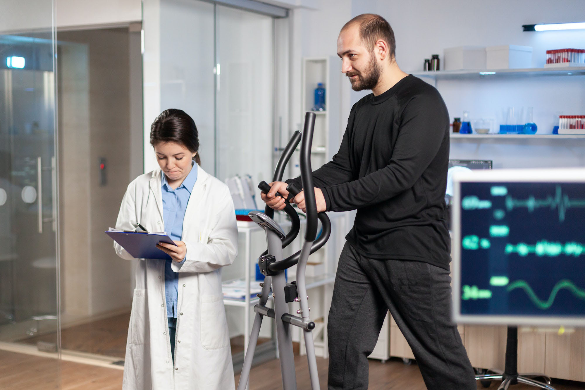 sport researcher in laboratory taking notes while muscular athlete athlete is running