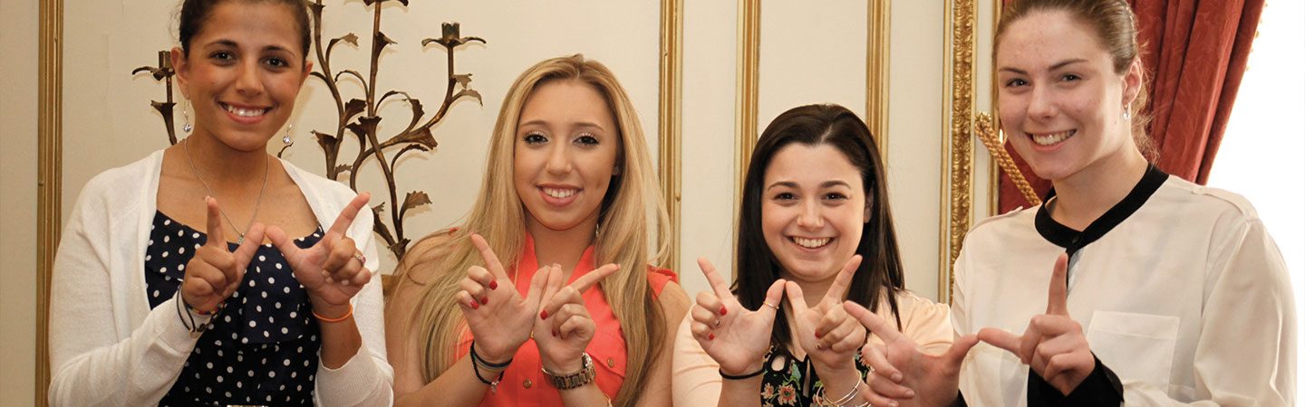 Four young women forming the letter W with their fingers
